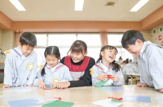 先生と折り紙をする園児達